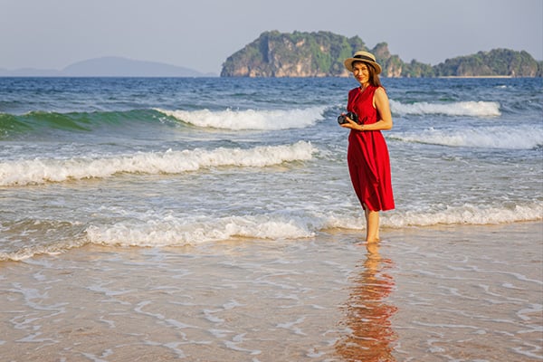 Woman photographer in red dress standing & soaking in water