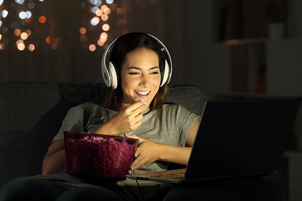 Lady eating popcorn, watching movie.