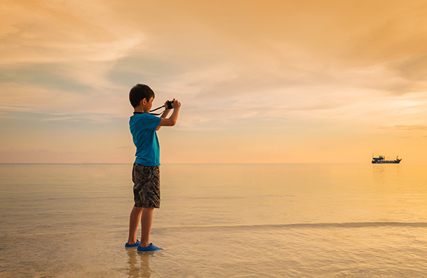 Boy with camera on beach: photography insurance Canada